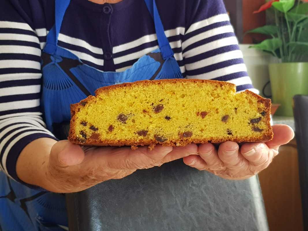 Hands holding orange cake with dried fruit
